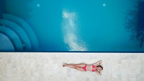 Private oasis woman lying on floor near pool 1460742 60th Anniversary 480